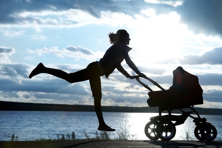 10430518 - silhouette of young slim mother doing exercise with a pram